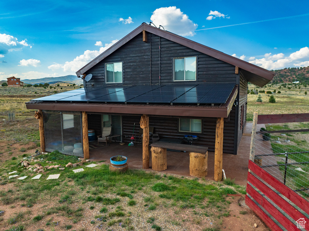 Rear view of property featuring a mountain view, a patio area, a rural view, and solar panels