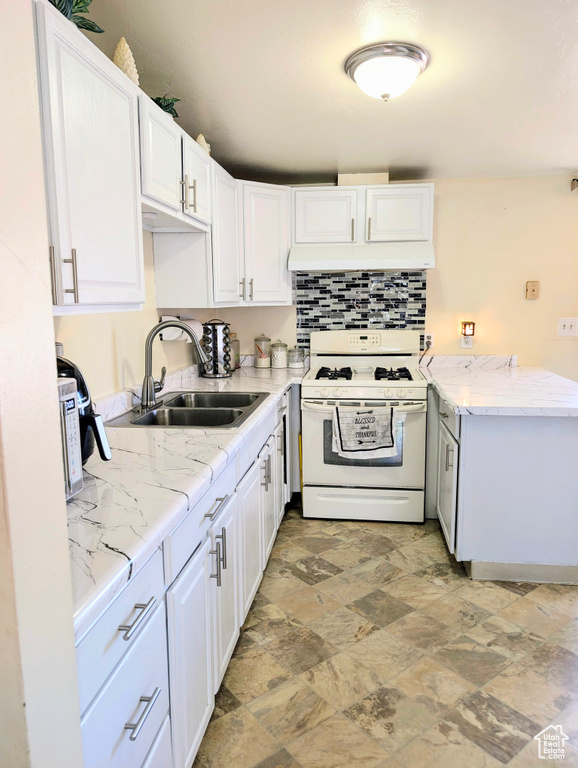 Kitchen with backsplash, custom exhaust hood, white cabinetry, sink, and white gas range oven