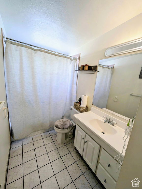 Bathroom featuring vanity, toilet, a shower with curtain, and tile patterned floors