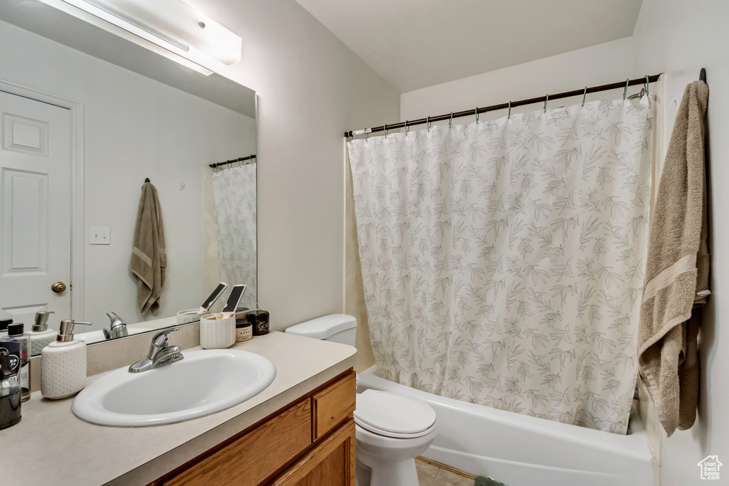 Full bathroom with vanity, shower / bath combo, and toilet