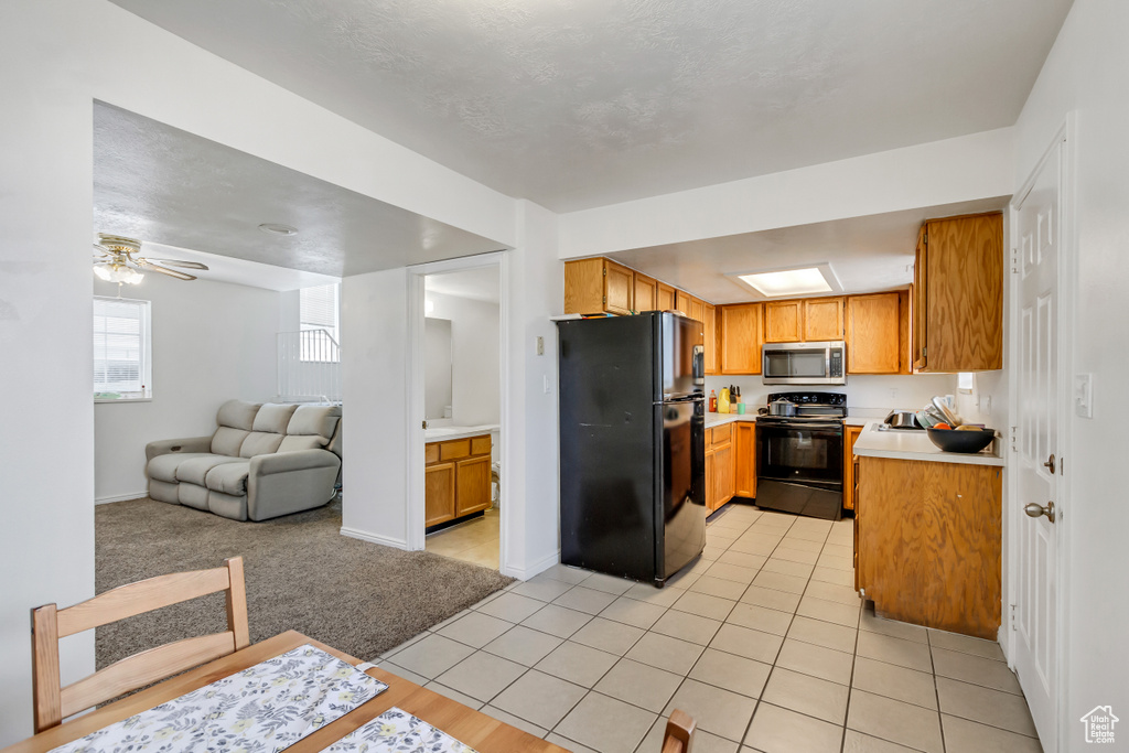 Kitchen featuring black appliances, light tile patterned floors, and ceiling fan