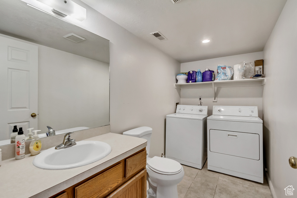 Bathroom featuring tile patterned flooring, washer and clothes dryer, toilet, and vanity