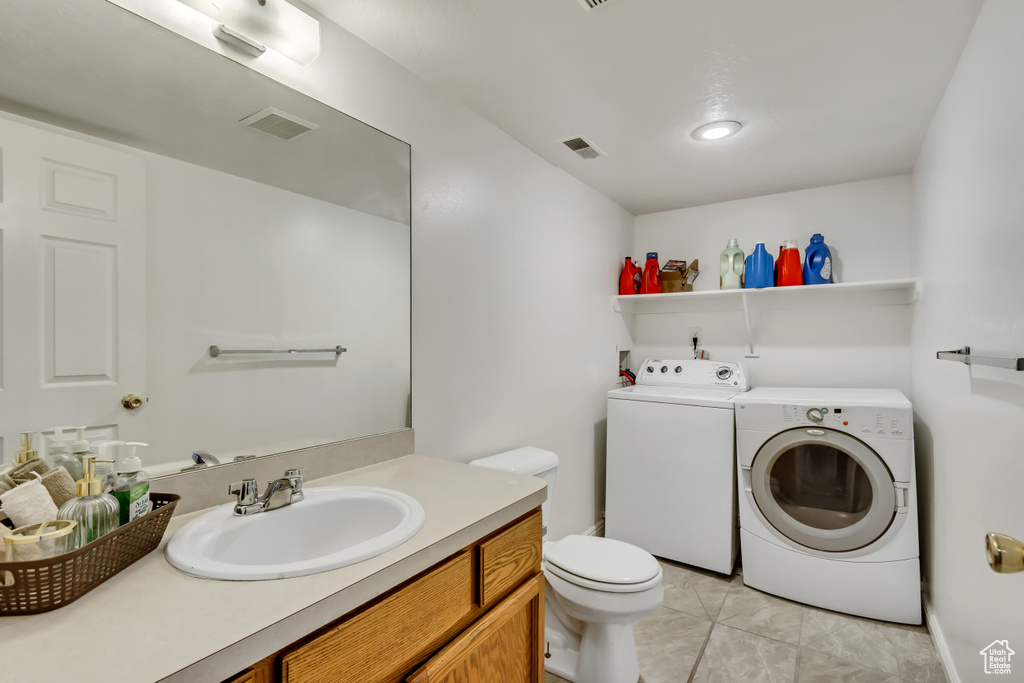 Bathroom featuring vanity, toilet, washing machine and dryer, and tile patterned flooring