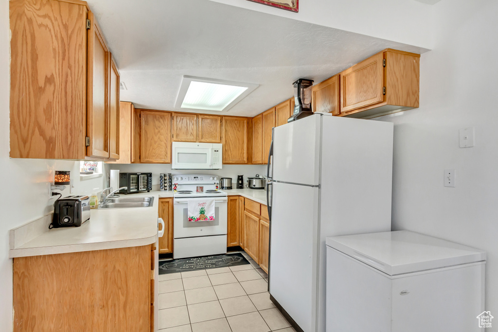 Kitchen with sink, light tile patterned floors, and white appliances