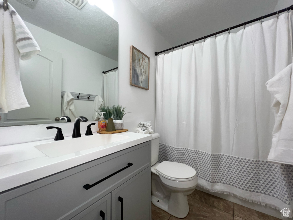 Bathroom featuring tile patterned floors, vanity, a textured ceiling, and toilet