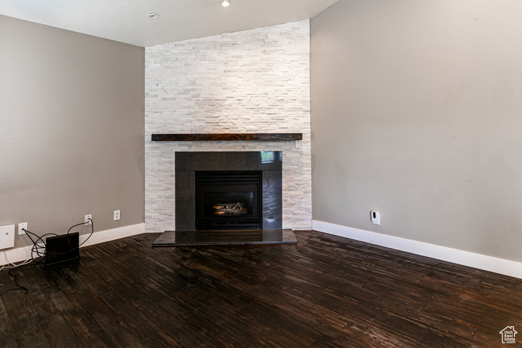 Unfurnished living room featuring a fireplace, hardwood / wood-style flooring, and vaulted ceiling