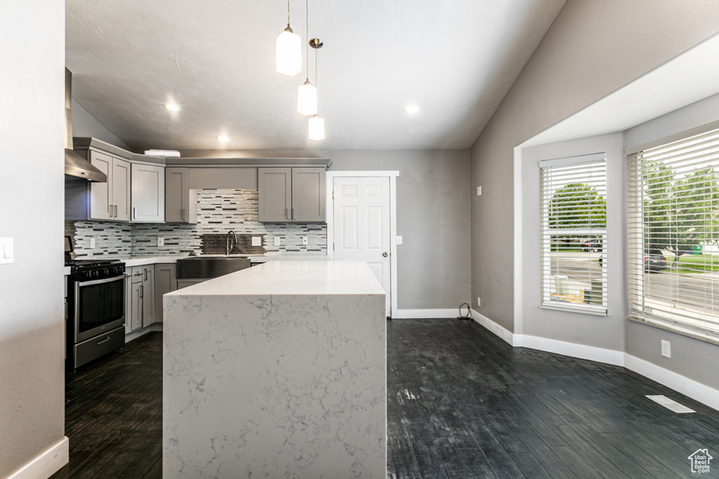 Kitchen with tasteful backsplash, dark hardwood / wood-style floors, hanging light fixtures, stainless steel range oven, and vaulted ceiling