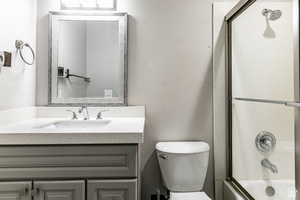 Full bathroom featuring vanity, shower / bath combination with glass door, and toilet