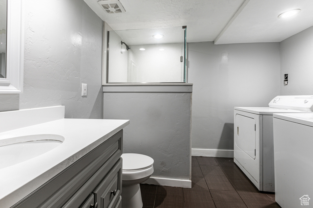 Bathroom featuring vanity, independent washer and dryer, and toilet