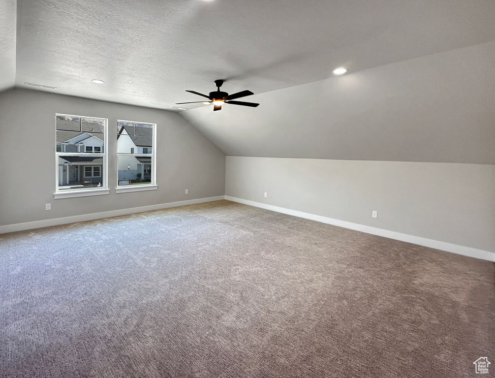 Additional living space featuring vaulted ceiling, carpet, and a textured ceiling