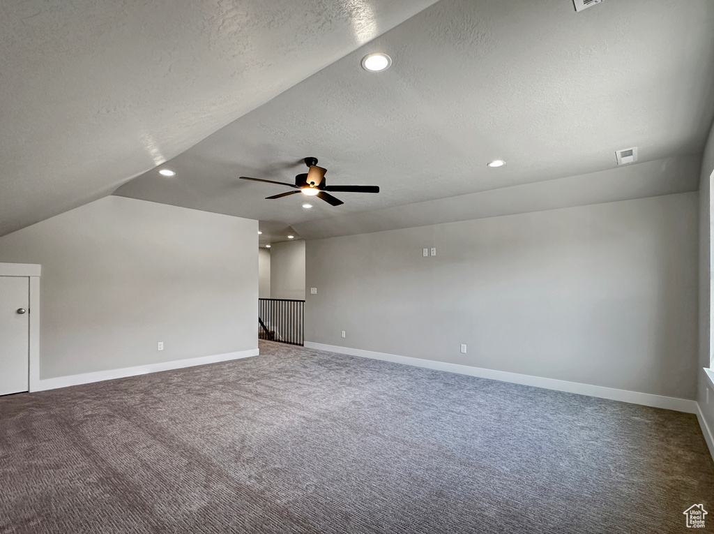 Interior space with vaulted ceiling, a textured ceiling, and ceiling fan