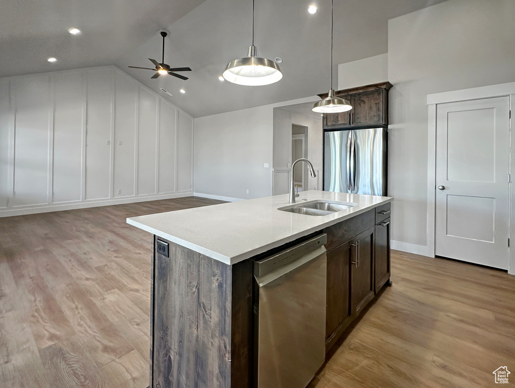 Kitchen with a kitchen island with sink, light hardwood / wood-style flooring, decorative light fixtures, sink, and appliances with stainless steel finishes