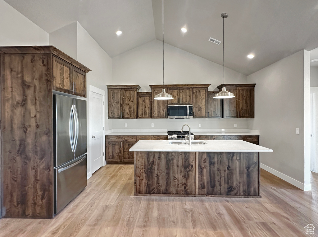 Kitchen with pendant lighting, stainless steel appliances, light wood-type flooring, and lofted ceiling