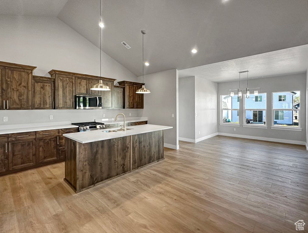 Kitchen with a kitchen island with sink, appliances with stainless steel finishes, sink, and light hardwood / wood-style flooring