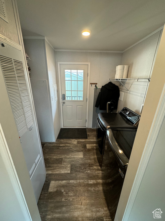 Clothes washing area featuring ornamental molding, washer and dryer, and dark hardwood / wood-style floors