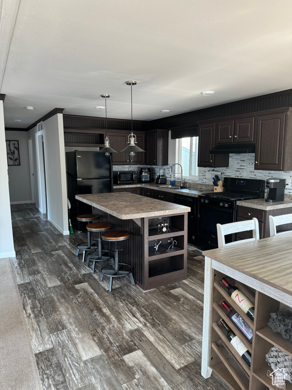 Kitchen with tasteful backsplash, dark brown cabinets, a kitchen island, black appliances, and decorative light fixtures