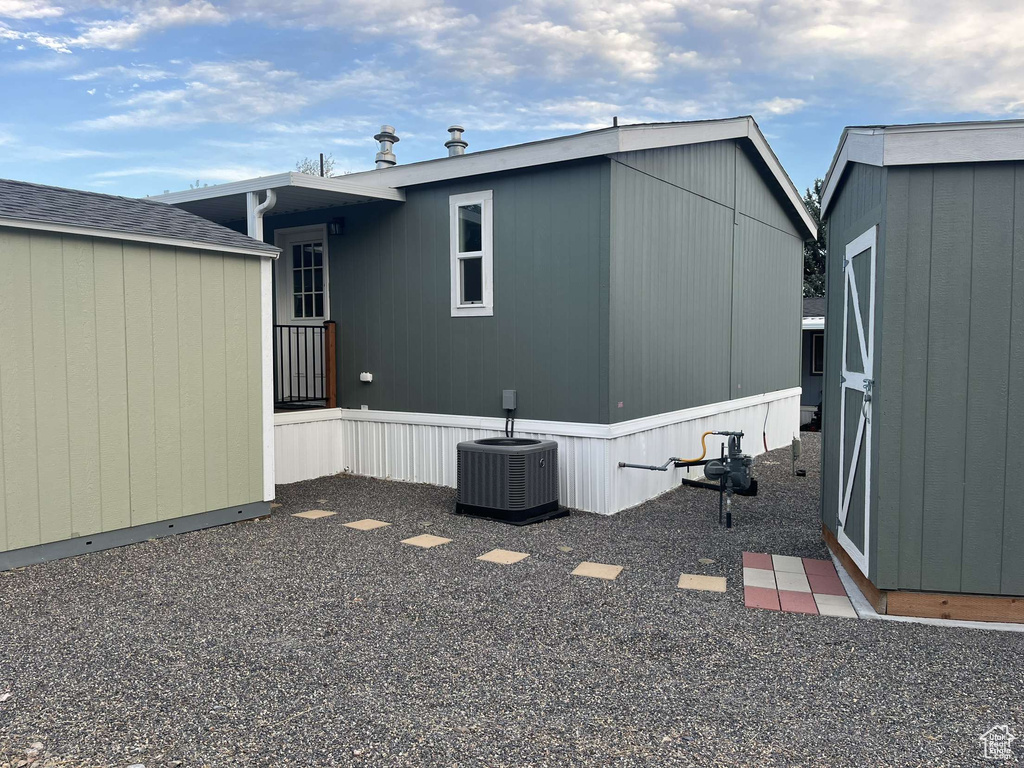 Rear view of property featuring a storage unit and central AC unit