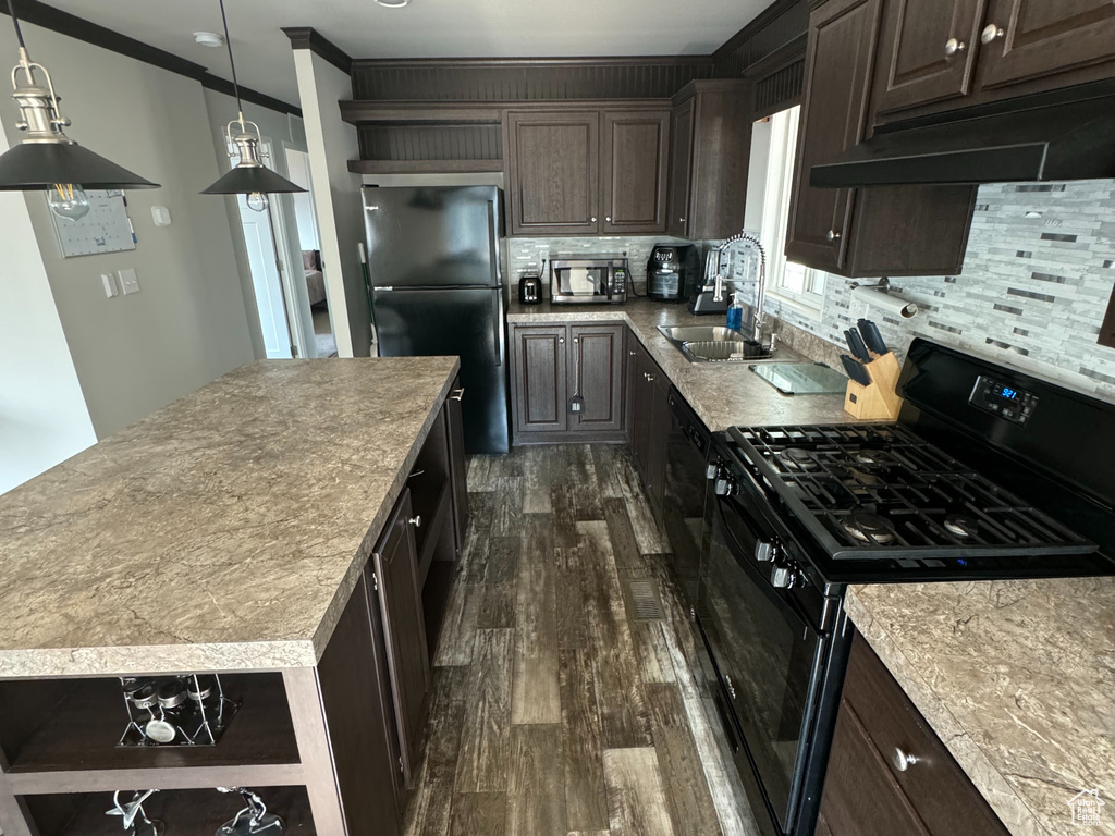 Kitchen with crown molding, backsplash, a kitchen island, black appliances, and hardwood / wood-style floors