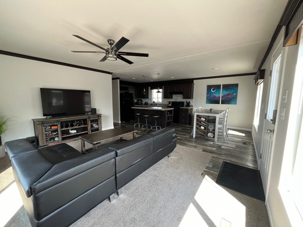 Living room featuring dark hardwood / wood-style flooring, ceiling fan, and ornamental molding