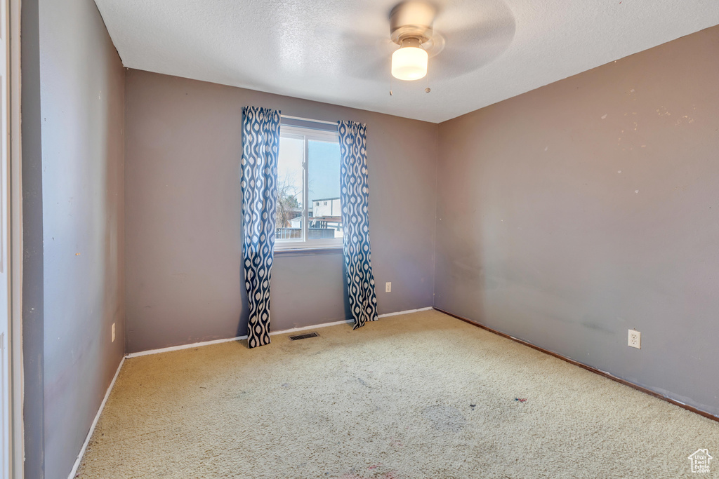 Empty room featuring carpet and ceiling fan