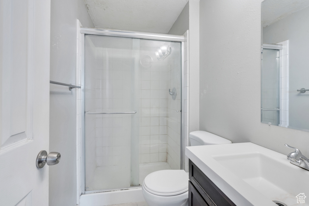 Bathroom featuring vanity, an enclosed shower, a textured ceiling, and toilet