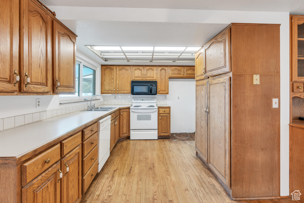 Kitchen with sink, light hardwood / wood-style flooring, and white appliances