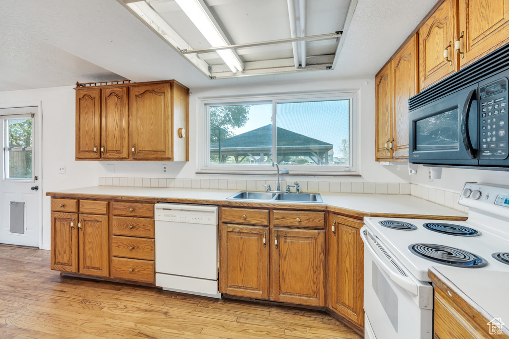 Kitchen featuring light hardwood / wood-style floors, white appliances, and sink