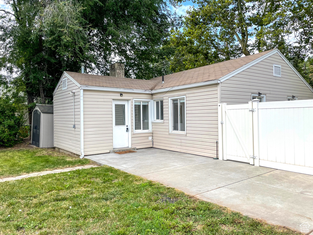 View of front facade with a patio area, a storage unit, and a front lawn