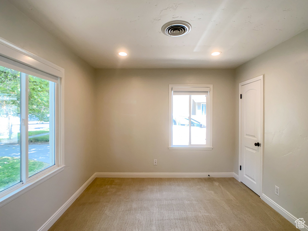 Empty room with a wealth of natural light and light colored carpet