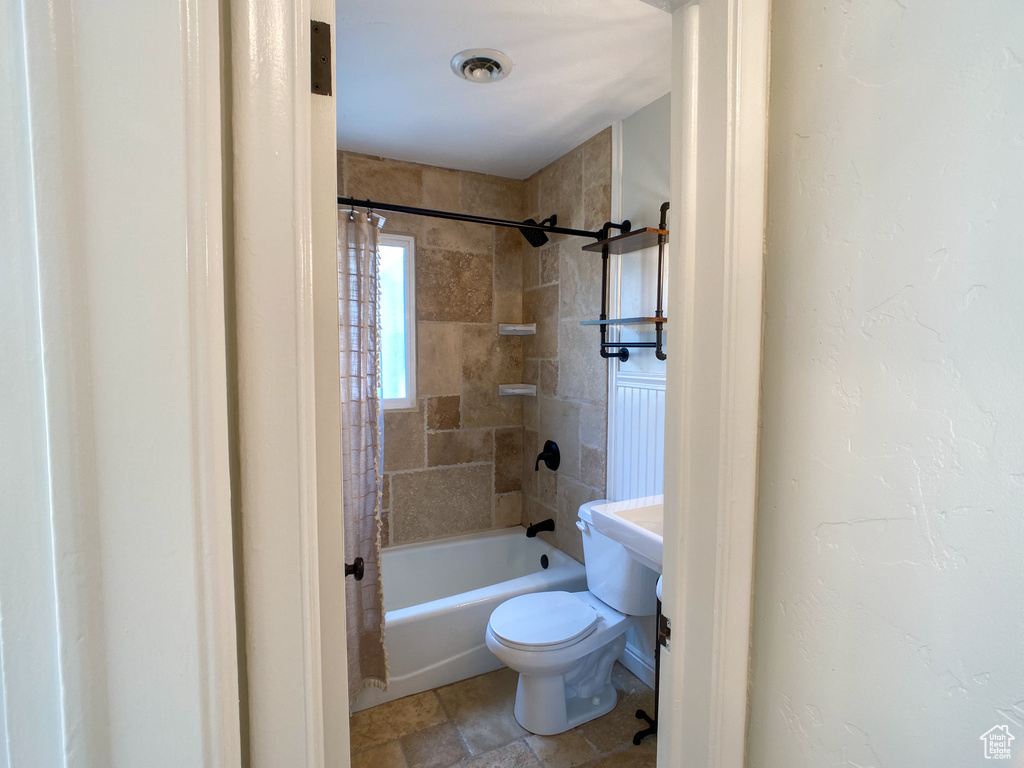 Bathroom with tile patterned floors, toilet, and shower / bath combination with curtain