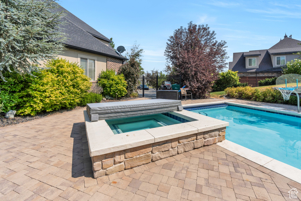 View of pool with a patio and an in ground hot tub