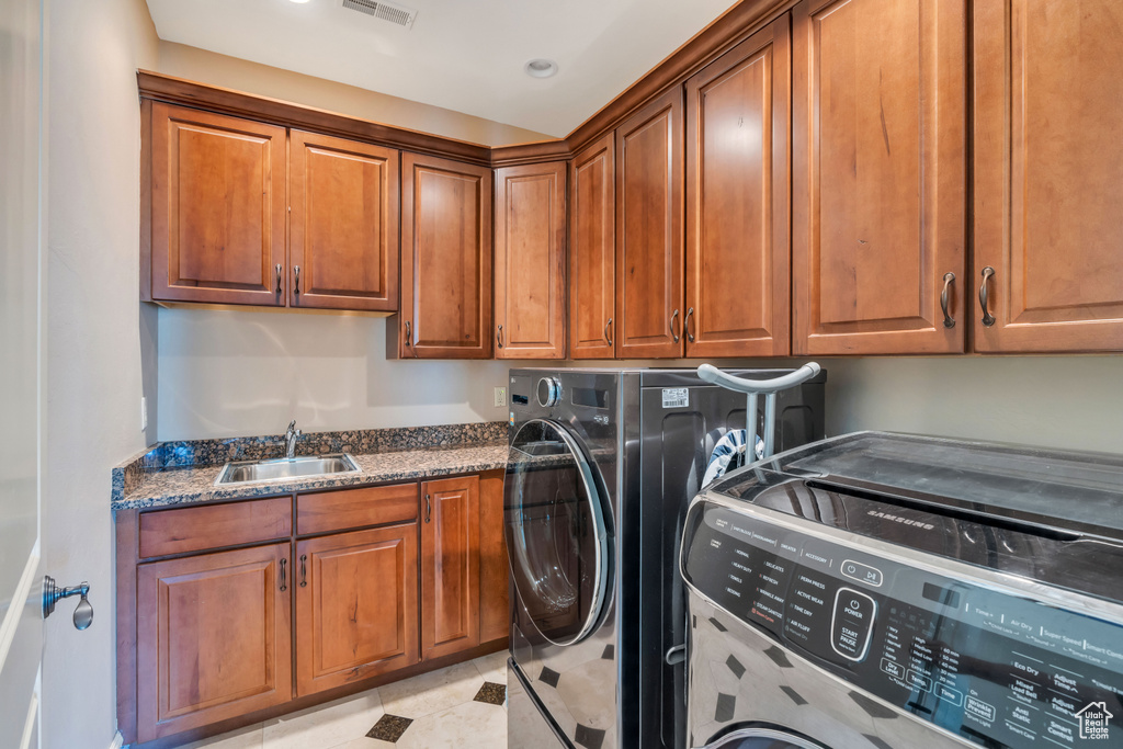 Washroom featuring light tile patterned floors, independent washer and dryer, cabinets, and sink