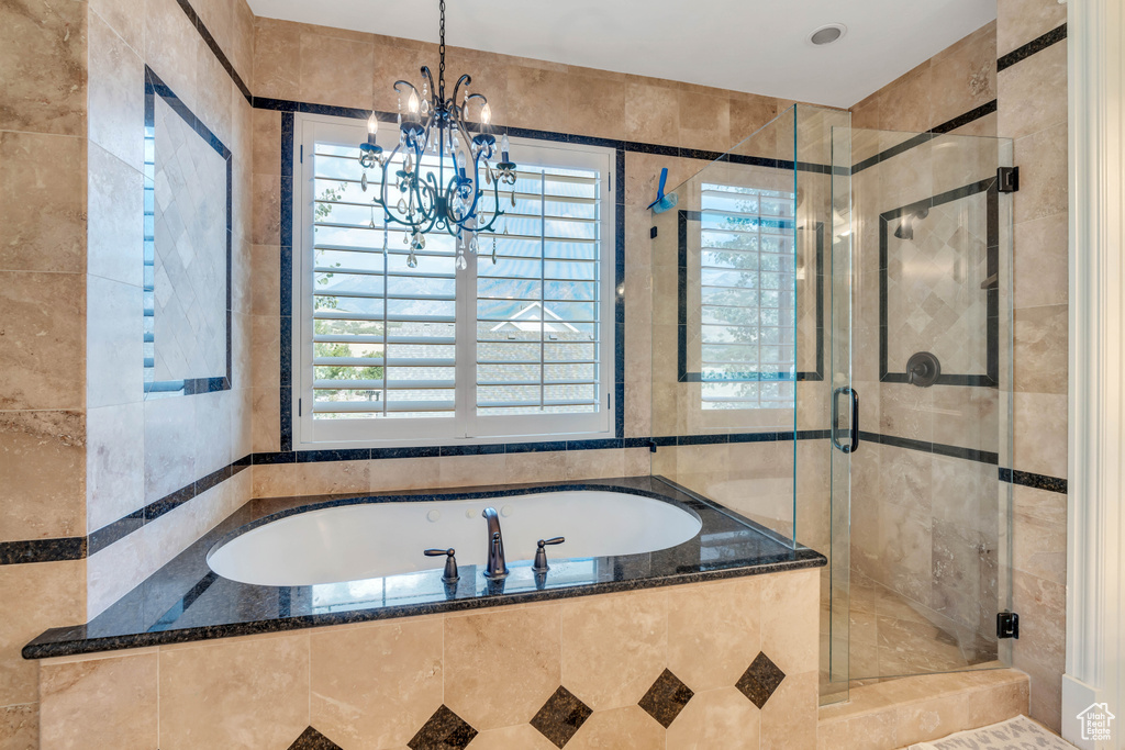 Bathroom featuring plus walk in shower and an inviting chandelier