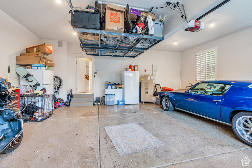 Garage featuring white fridge and a garage door opener