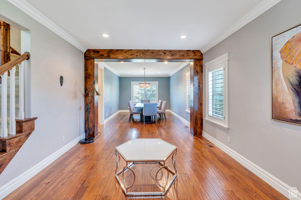 Interior space with an inviting chandelier, hardwood / wood-style flooring, and ornamental molding