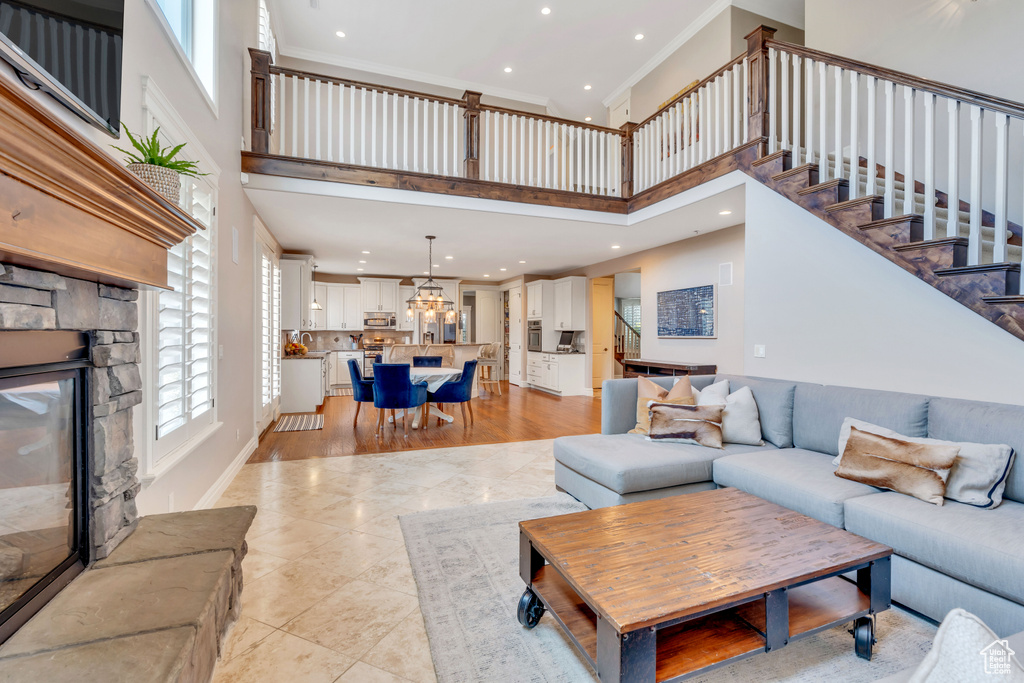 Living room featuring a fireplace, a towering ceiling, light wood-type flooring, and ornamental molding