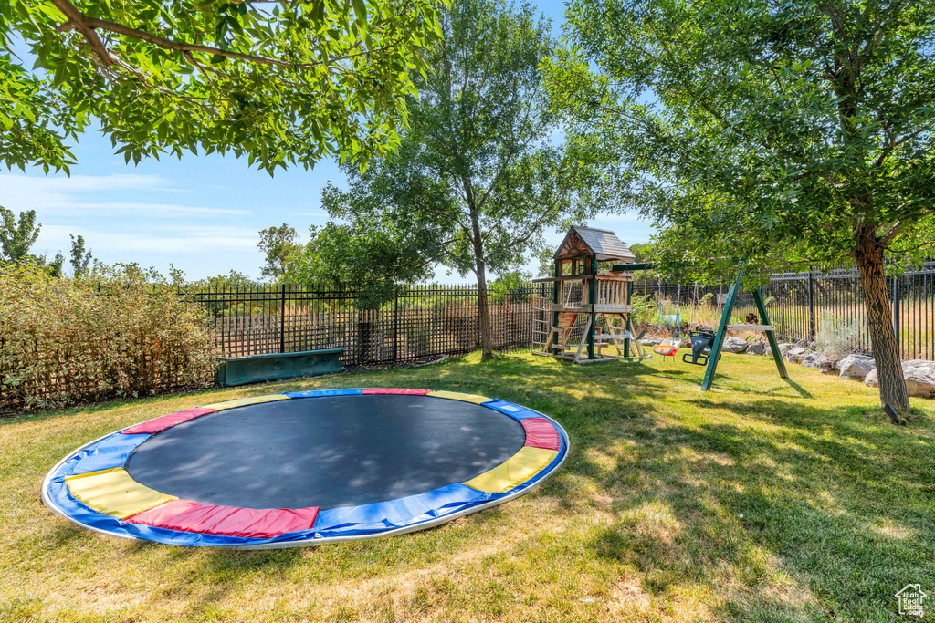 View of swimming pool featuring a playground, a trampoline, and a lawn