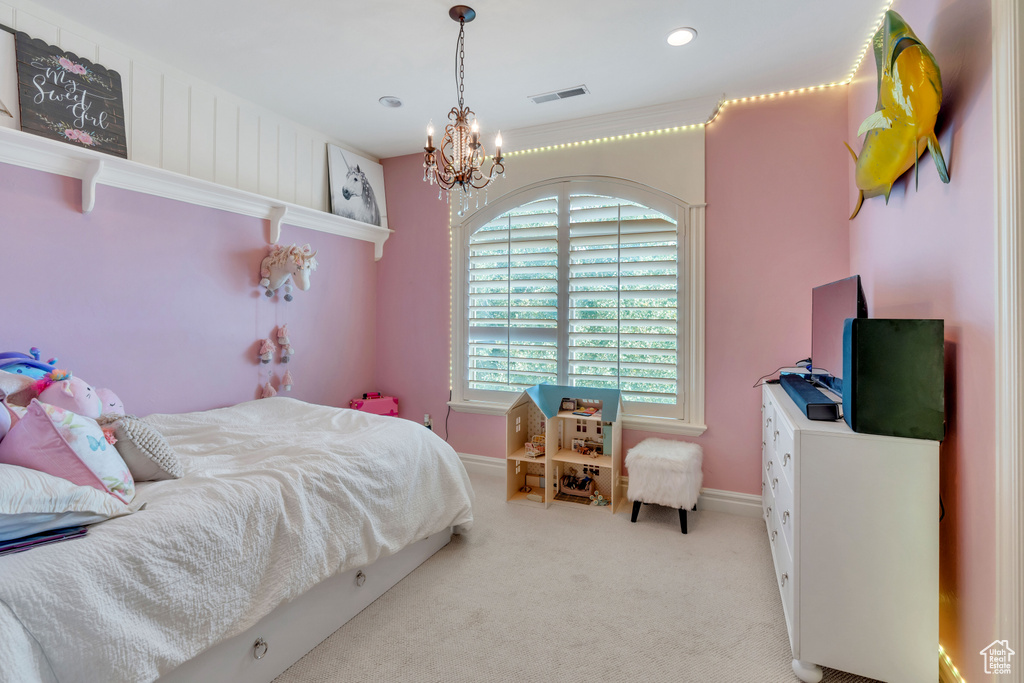 Bedroom with a notable chandelier and light colored carpet