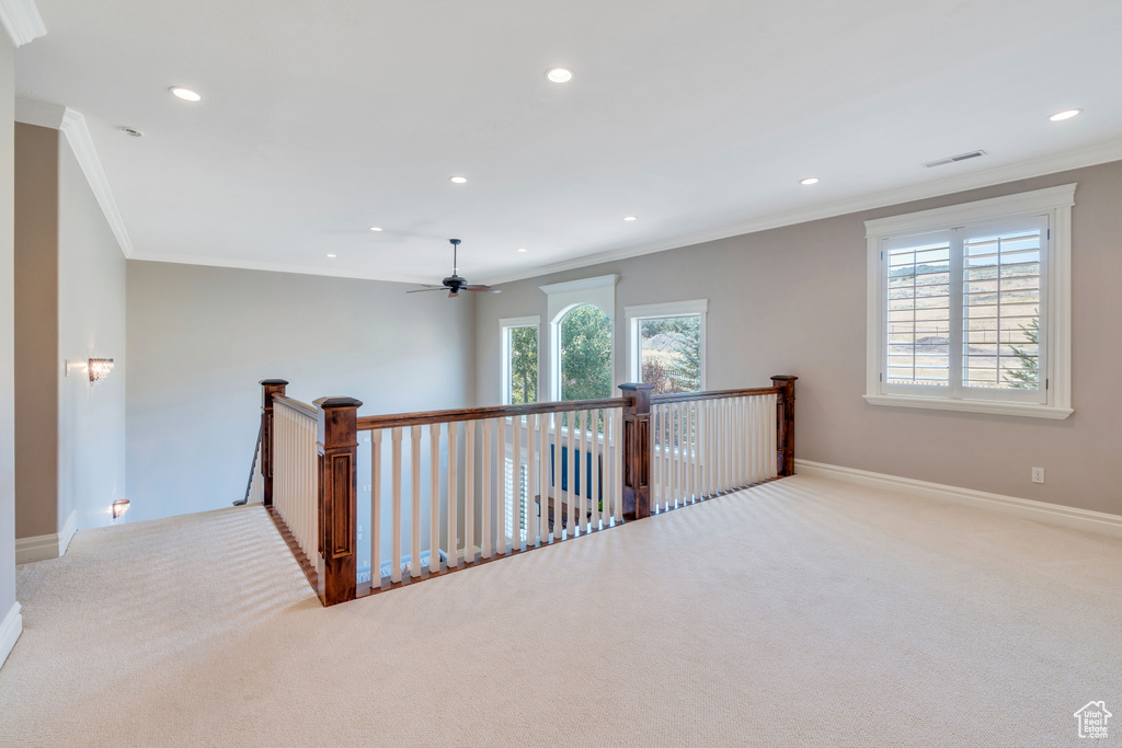 Corridor with a healthy amount of sunlight, ornamental molding, and light colored carpet