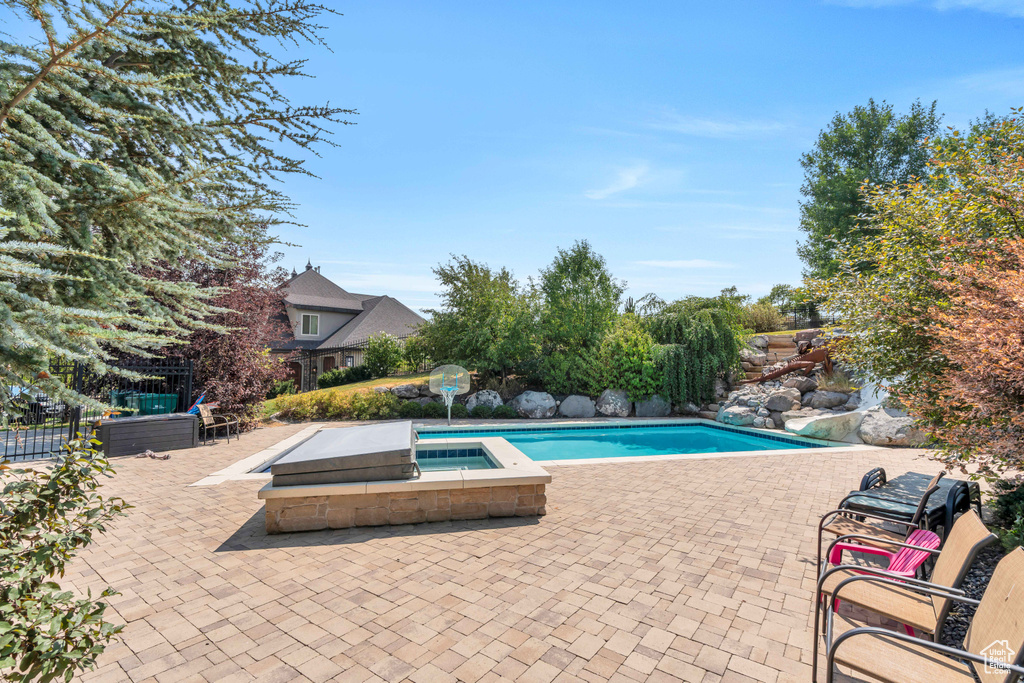 View of swimming pool with a patio and an in ground hot tub