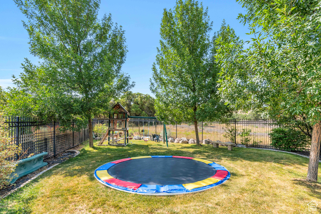 View of yard featuring a trampoline and a playground