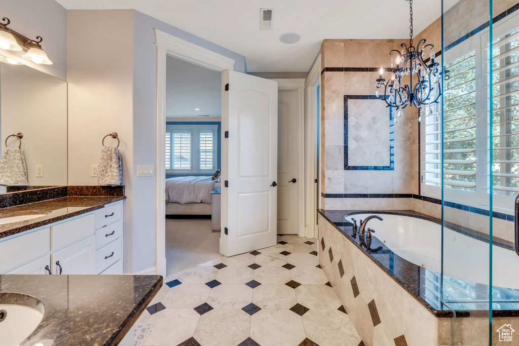 Bathroom featuring a relaxing tiled tub, tile patterned floors, a notable chandelier, and vanity