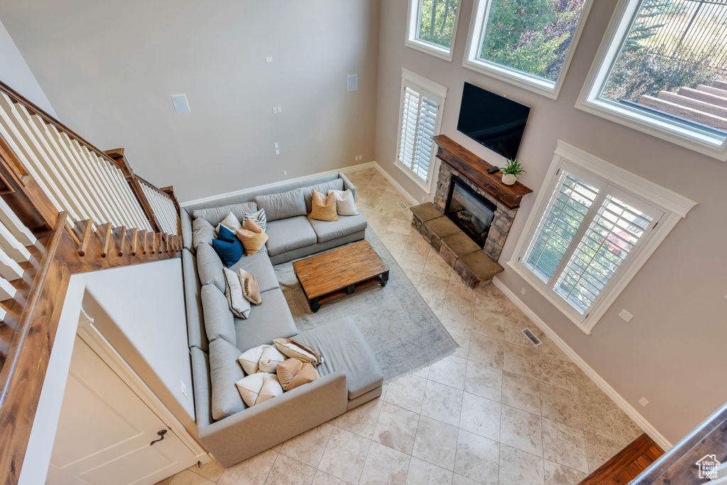 Living room featuring light tile patterned flooring, a wealth of natural light, and a high ceiling