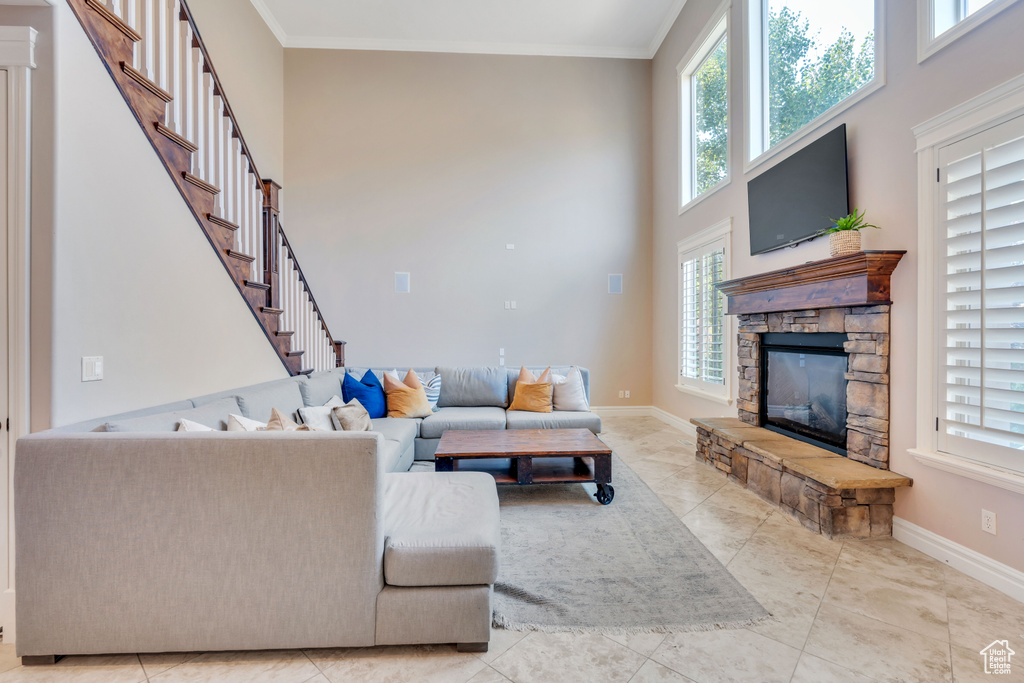 Living room featuring light tile patterned flooring, a high ceiling, a fireplace, and ornamental molding