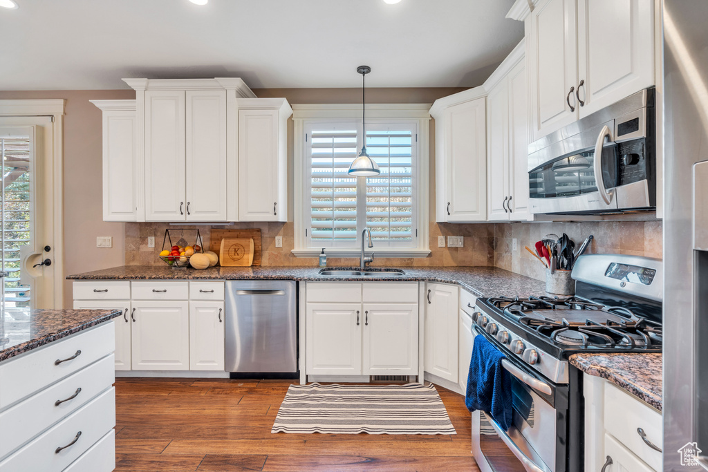 Kitchen featuring sink, white cabinetry, decorative backsplash, and stainless steel appliances