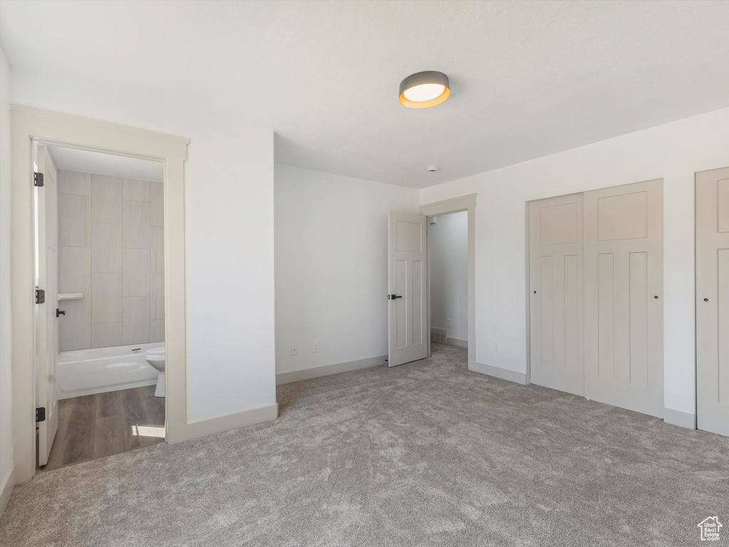 Unfurnished bedroom with ensuite bath and carpet