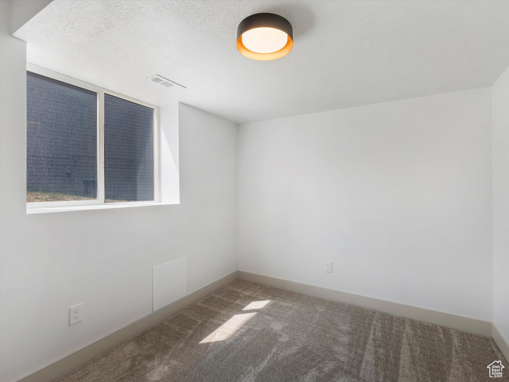 Carpeted spare room featuring a textured ceiling