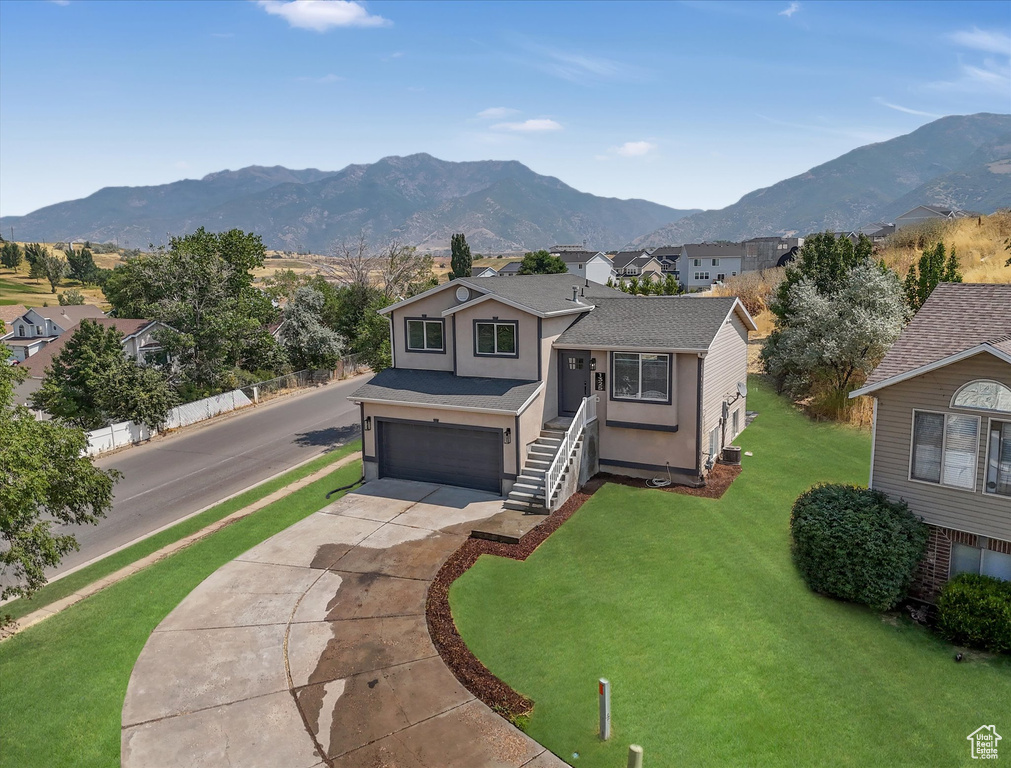 View of front facade with a garage, a mountain view, and a front lawn