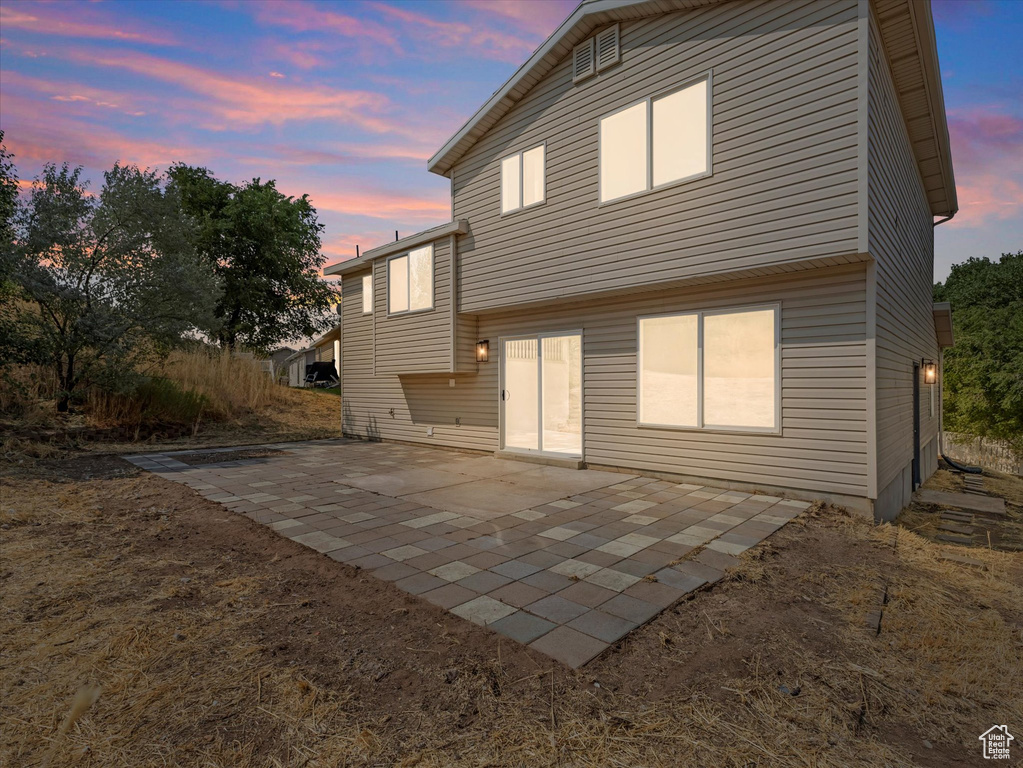 Back house at dusk featuring a patio area