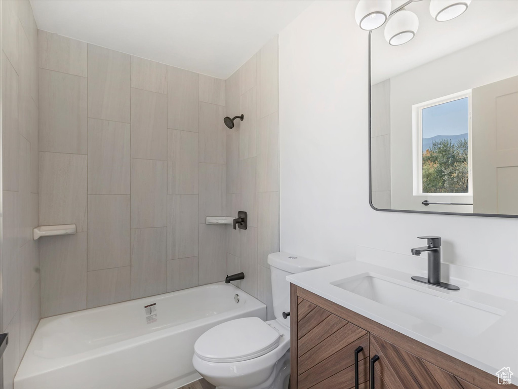 Full bathroom with toilet, vanity, and tiled shower / bath